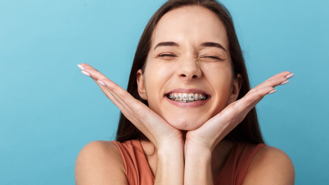 Smiling young woman with braces, hands framing face