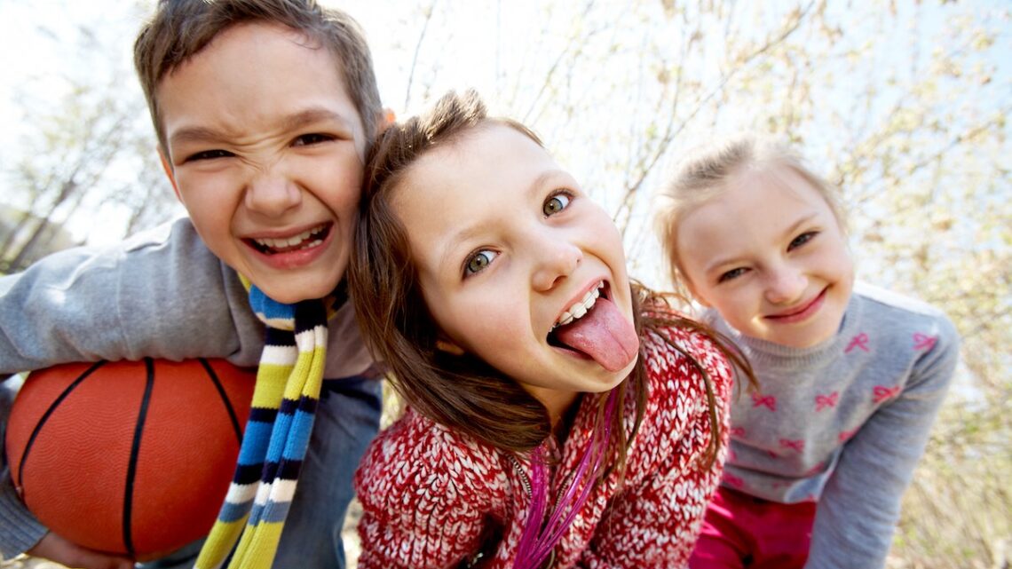 Three playful children outdoors with basketball