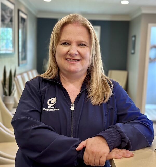 Smiling woman in orthodontic clinic jacket